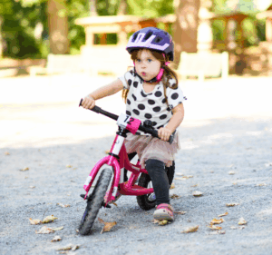 Das Bild illustriert, dass Kinder mit einem Laufrad glücklich sind und Freude an der Bewegung haben.