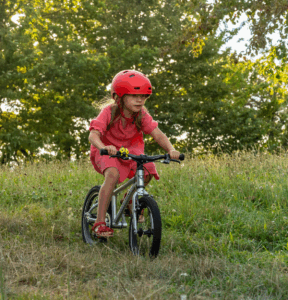 Das Bild zeigt wie Kinder mit Lauf- und Fahrrad viel Freude haben.